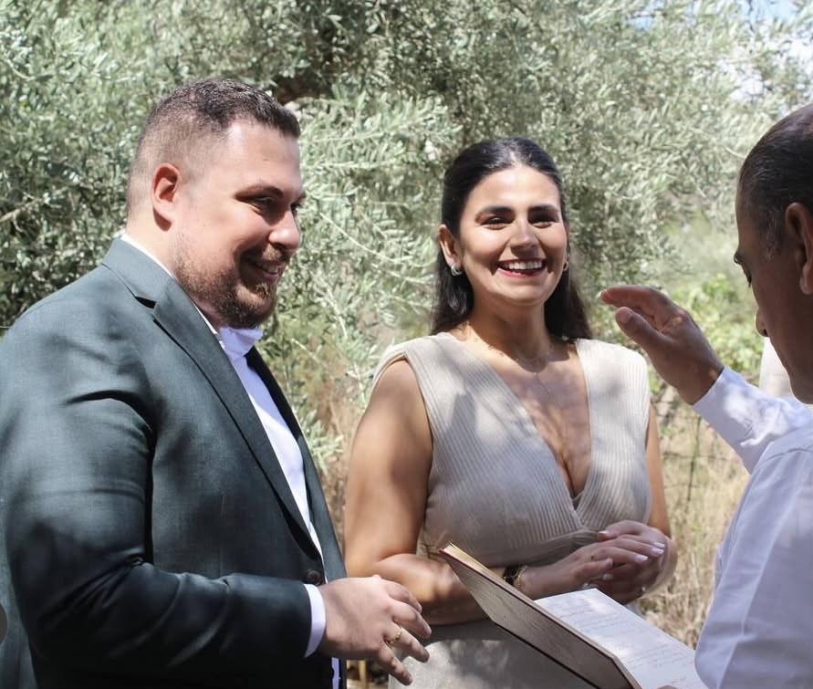 Roger and Rita exchanging rings under olive trees.
