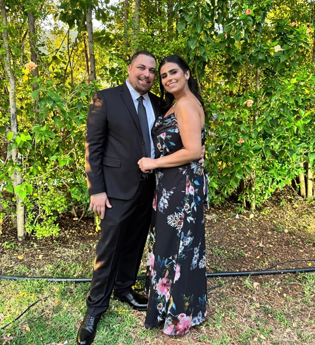 Roger and Rita dressed up at an evening reception under palm trees.